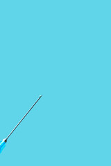 needle of syringe with vaccine on blue background