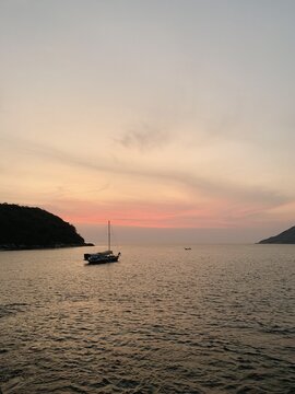 Lone Old Fisher Boat In The Sea With View On Islands And Blue Sky At Sunset Or Sunrise