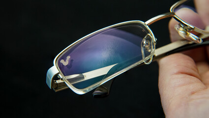 The goggle with scratched lenses. A human hand holds the glasses with damage of the scratches on...