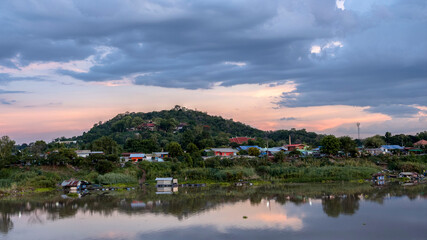 A village on the river side with a temple on the other side of the mountain.