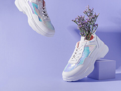 White female sneakers with sequins with flowers inside on purple background with geometric cube podium