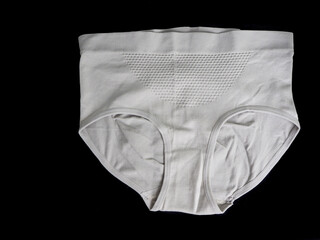 close beige seamless female high-waisted panties lie on a black background top view. women panties with microfiber