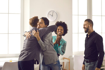 Group of positive diverse people hugging their friend or colleague. Team of office workers embracing young man congratulating him on promotion or happy life event - Powered by Adobe