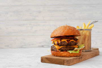 Double cheeseburger served on wooden board against white blurred background