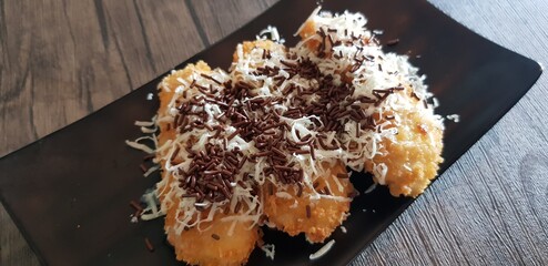 Fried Crumble Crispy Banana with chocolate and cheese on the black plate with wooden table background