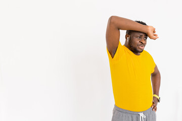 Tired afro american guy feeling tired after difficult online workout exercising in headphones wearing yellow t-shirt. Sport beginner exhausted working out at home.