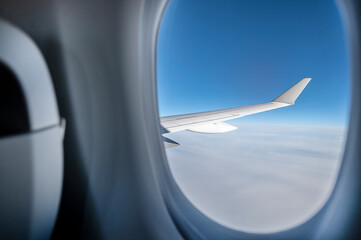 Fototapeta na wymiar Airplane wing in blue sky through window