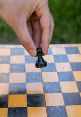 Male hand holding one chess piece of black pawn over empty chessboard