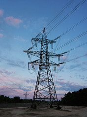 silhouette of high voltage power lines against a colorful sky at sunrise.