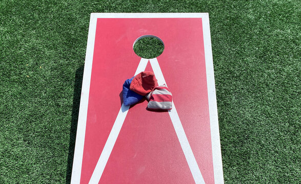 Close up of a red and white cornhole game with three beanbags