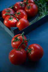 Fresh tomatoes illuminated by the light coming through the window, on a blue background.