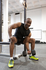 Naklejka na ściany i meble African American man strengthening his body doing weight training in gym. Fitness concept.