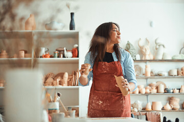 Charming woman in apron working in pottery workshop