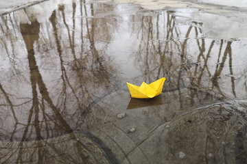 Paper origami. A yellow ship floats on the water. Spring Games