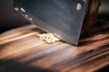 Close-up of chopped or minced fresh ginger (Zingiber officinale) on a wooden cutting board  with a...