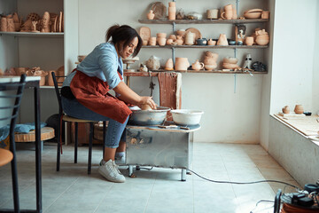 Charming young woman making pottery in workshop