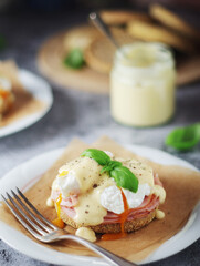 Egg benedict sandwiches - muffin with poached egg, ham and hollandaise sauce