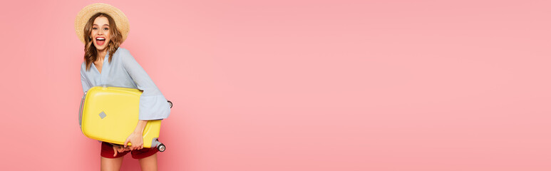 Happy woman in sun hat holding suitcase on pink background, banner