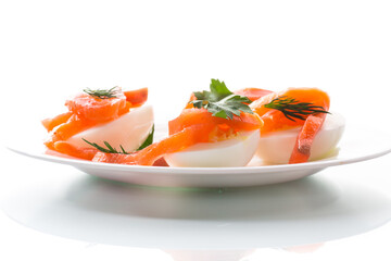 halves of boiled eggs with pieces of salted salmon on white background