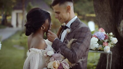 Wedding ceremony of a multi ethnic couple. Bride and groom in wedding dresses are getting married in a summer park