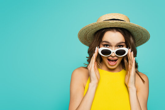 Excited Woman In Straw Hat Holding Sunglasses Isolated On Blue