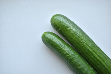 Two green long cucumbers on a white background