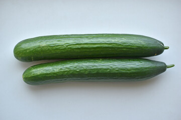 Two green long cucumbers on a white background
