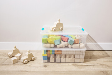 Wooden cubes, kids toys sorted in plastic containers, stand on the floor in the nursery room....