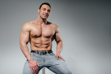 Fototapeta premium A young athlete in jeans poses sitting in the studio. Sport.