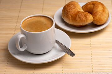 Morning aromatic coffee with two fresh croissants on a white plate on a napkin made of natural bamboo Selective focus
