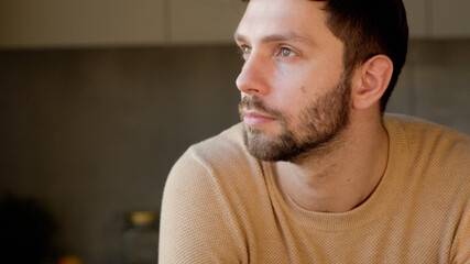 Young man in the kitchen close up. Handsome man thinking about idea