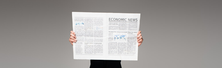 Naklejka premium man covering face while reading economic news on grey, banner