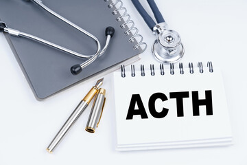 On the table are a stethoscope, a pen and a notebook with the inscription - ACTH