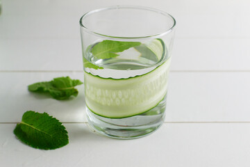 A glass of detox water infused with cucumber and mint, with ingredients. Health care, fitness, healthy food concept.