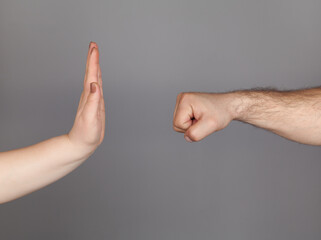 Stop violence against women campaign. Woman using hand palm to stop man's punch from attack isolated, on gray background.
