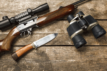 Hunting rifle and binoculars on dark wooden background