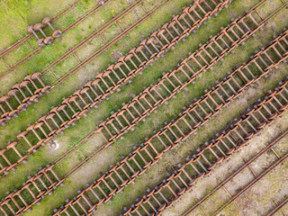 Wheels on railway tracks. Aerial drone top view. Green grass background.