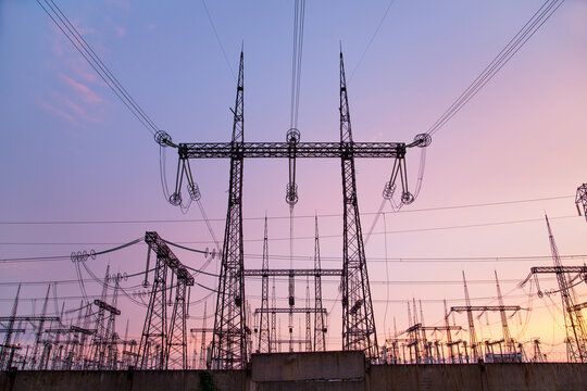 An extra-high voltage substation against the backdrop of a pink sunset.