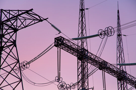 An extra-high voltage substation against the backdrop of a pink sunset.