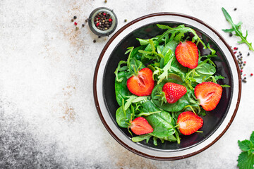 green salad strawberry leaves salad mix arugula, spinach organic healthy food meal snack copy space food background rustic. top view diet vegan or vegetarian food