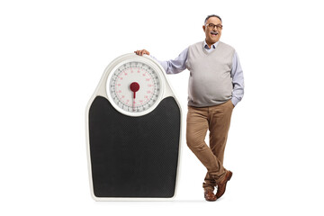 Full length portrait of a corpulent mature man leaning on a big weight scale