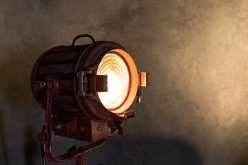 Old movie projector with a lens and a hot lamp.Vintage lamp projector near the grey wall. Room in...