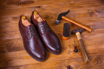 Pair of shoes on a wooden background with instruments. Shoe production