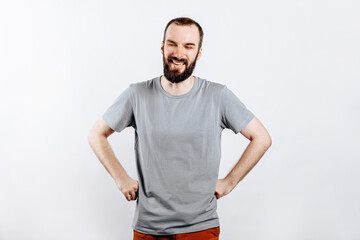 Portrait of cheerful young man smiling while looking at camera holding hands out to sides on white background with space for advertising mock up
