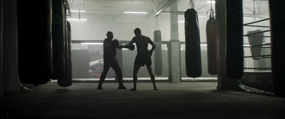 WIDE Caucasian male boxer practicing with his trainer in a boxing gym, preparing for a fight. Shot with 2x anamorphic lens - Powered by Adobe