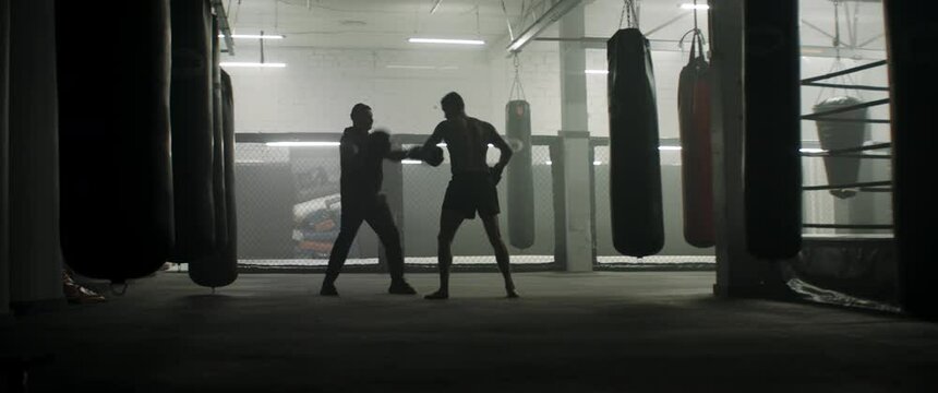 WIDE Caucasian male boxer practicing with his trainer in a boxing gym, preparing for a fight. Shot with 2x anamorphic lens