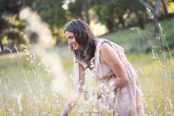 Happy woman picking wildflowers with wicker basket