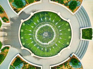 An aerial overhead view of a city fountain in a small park.