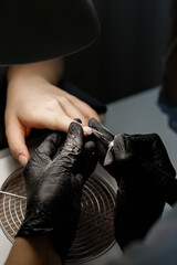 Fototapeta premium The manicurist makes a manicure with a saw in the salon. close-up
