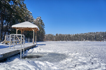 Frozen lake with ladder and bridge. Ice hole made near the ladder. 